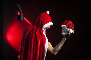 2021 yılının kırmızı Noel Baba pelerinli, baltalı ve metal boğa heykelciği sembollü bir adam.