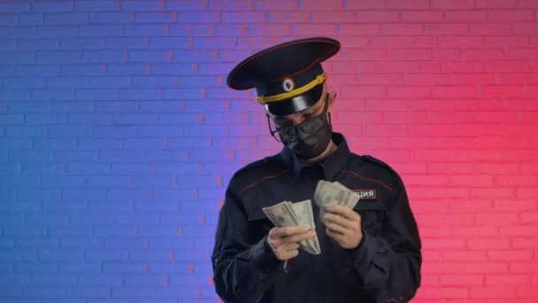 A man in a Russian police military uniform with a coronavirus mask counts the bribe dollars and returns the documents — Stock Video