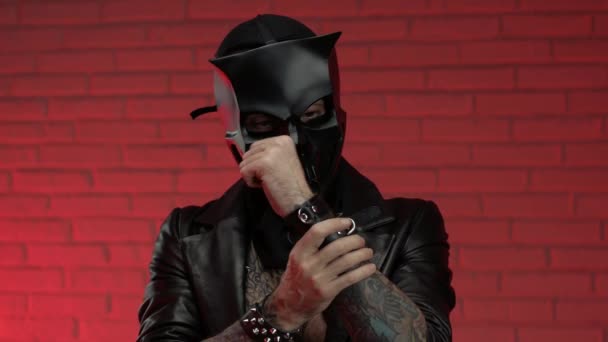 Een man in een duivelse schedel masker draagt een leren mantel met leren armbanden en riemen op zijn lichaam — Stockvideo