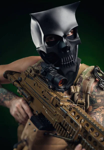 A man in a skull mask with a machine gun in his hands in tattoos — Stock Photo, Image