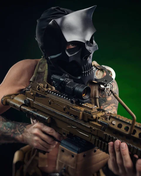 Een man met een schedelmasker met een machinegeweer in zijn handen in tatoeages — Stockfoto