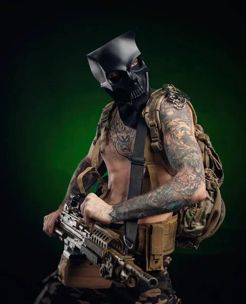 A man in a skull mask with a machine gun in his hands in tattoos — Stock Photo, Image