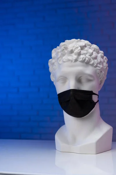Eine Statue aus weißem Gips, die eine medizinische Einmalmaske trägt, die ihr Gesicht bedeckt — Stockfoto