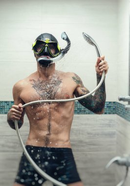 Duşta dalgıç maskesi takan bir adam suyla ıslanır.