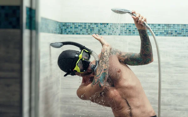 Um homem usando uma máscara de mergulho no chuveiro é molhado com água — Fotografia de Stock