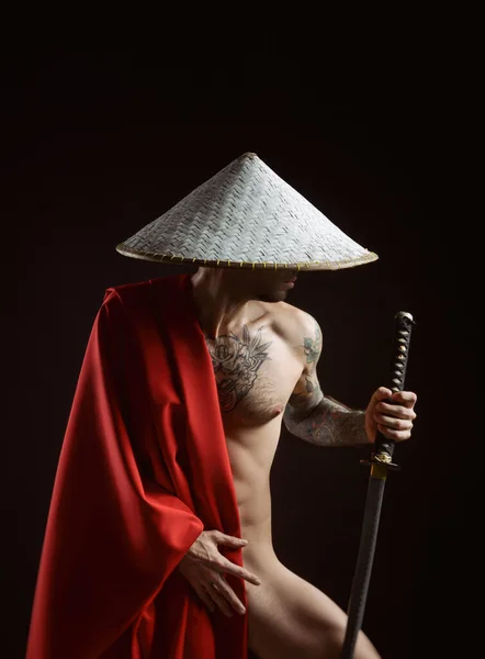a naked slender man samurai in a red cape and an Asian hat with a tattooed katana