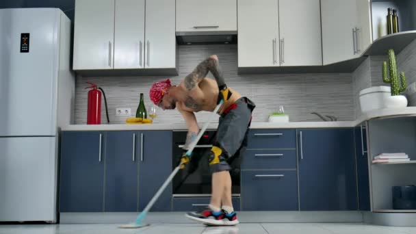 Парень, который работает в компании по уборке, убирает пол на кухне и танцует — стоковое видео