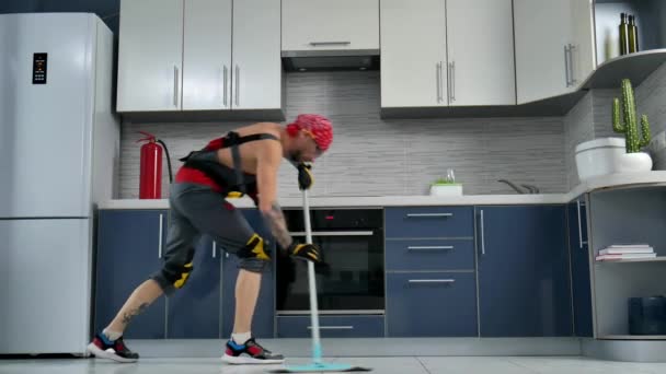 Парень, который работает в компании по уборке, убирает пол на кухне и танцует — стоковое видео