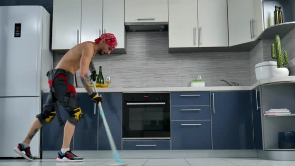 Um cara que trabalha para uma empresa de limpeza, limpa o chão da cozinha e dança — Vídeo de Stock