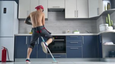 a guy who works for a cleaning company, cleans the kitchen floor and dances