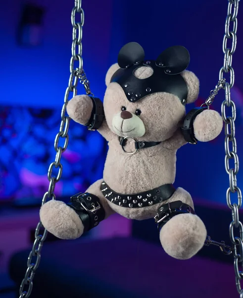 Orso giocattolo in una cintura di pelle accessorio per i giochi BDSM nella stanza al neon — Foto Stock