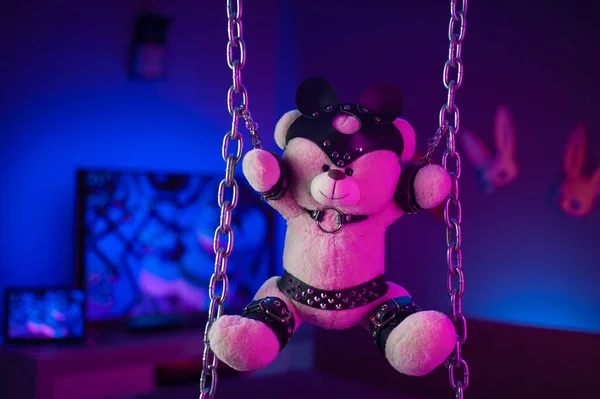 toy bear in a leather belt accessory for BDSM games in the neon room