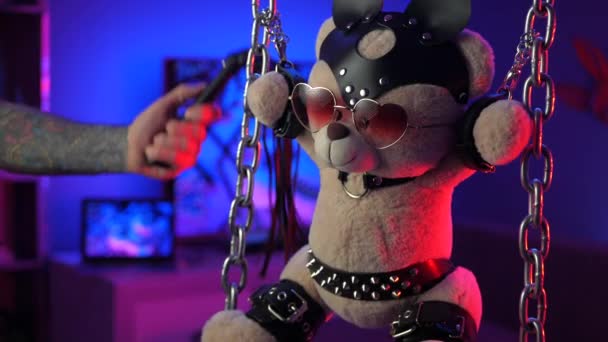 Teddybjörn i läderselar BDSM tillbehör hand i neonljus — Stockvideo