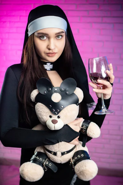 Uma mulher em um traje de freira sexy com um ursinho de pelúcia vestido com acessórios para jogos de bdsm — Fotografia de Stock