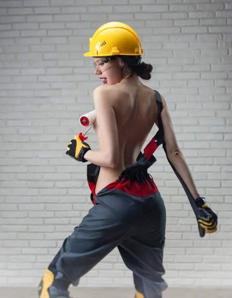 半裸の女性と塗装ローラー付きの建設ヘルメット — ストック写真