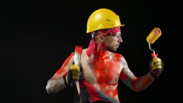 Un homme un peintre un plâtrier dans un casque et des salopettes peintes avec de la peinture vive danse joyeusement — Video