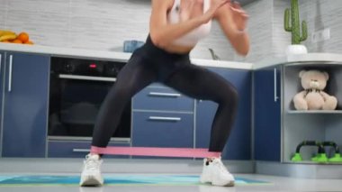 Kadın fitness eğitmeni aboneler için mutfakta online antrenman yapıyor.