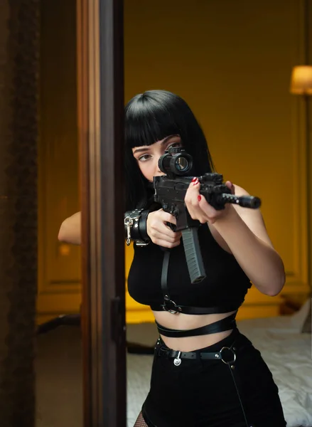 Женщина-киллер в отеле рядом с окном направляет автоматическую винтовку с телескопическим прицелом на жертву, совершившую убийство — стоковое фото