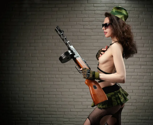 Žena v sexy vojenské uniformě se samopalem PPSH-41 z druhé světové války je oblečena v krátké sukni a kožených opaskech — Stock fotografie