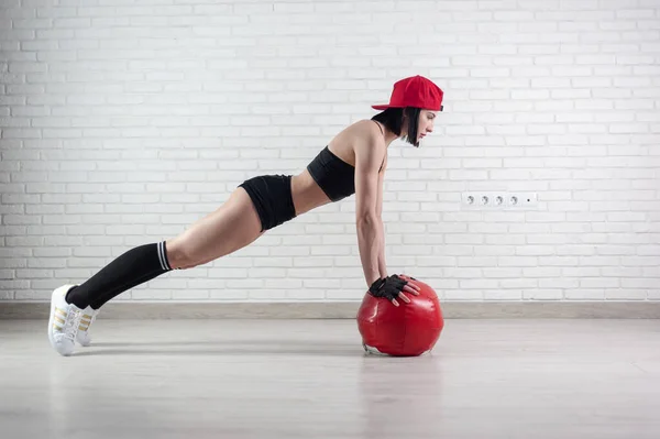 Athletic strong woman in sportswear trains with a fitness ball on a light background — Foto de Stock