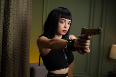 a female hitman in a hotel aims a gun at a victim with a scared face