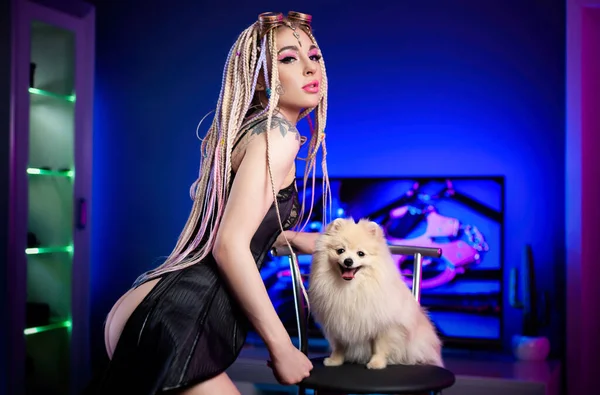 Retrato de uma mulher sexy com dreadlocks em um espartilho com um cão bonito pomeranian — Fotografia de Stock