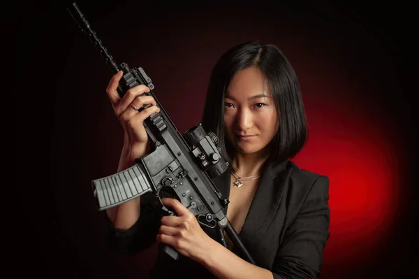 Mujer asiática en una chaqueta con un rifle automático en sus manos luchador mafia — Foto de Stock