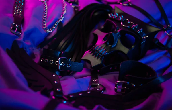 Bdsm iblisinin maskesi ve bdsm oyunları için deri aksesuarlar neon ışıkta karanlık bir arkaplanda — Stok fotoğraf