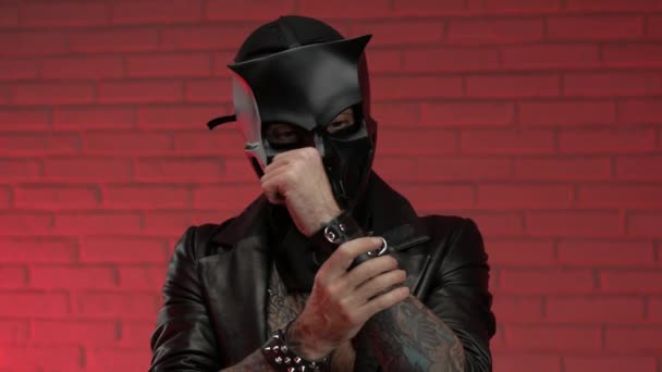 Человек в маске из черепа демона bdsm, одетый в кожаный плащ с кожаными браслетами и ремнями на теле — стоковое видео