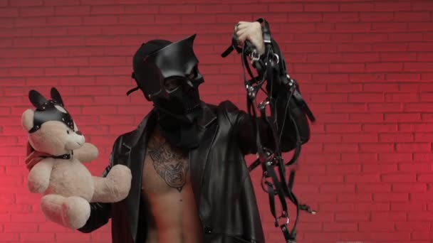 Un uomo in una maschera demone teschio bdsm, vestito con un mantello di pelle con bracciali in pelle e cinghie sul suo corpo — Video Stock
