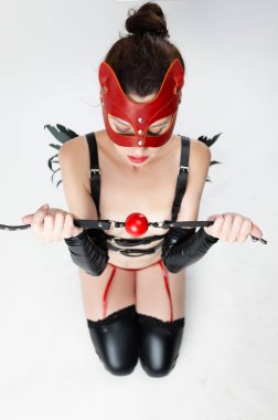 Deri kedi maskeli bir kadın cinsel oyunlar için BDSM elinde bir ağızlık topu tutuyor.
