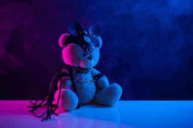 Deri kemer takmış oyuncak ayı. Koyu arkaplanda bdsm oyunları için aksesuar.