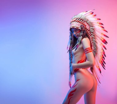 Amerikan yerlisi kostümlü çıplak bir kadın. Arka planda tüyleri var.
