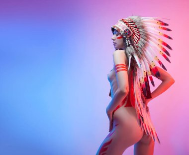 Amerikan yerlisi kostümlü çıplak bir kadın. Arka planda tüyleri var.