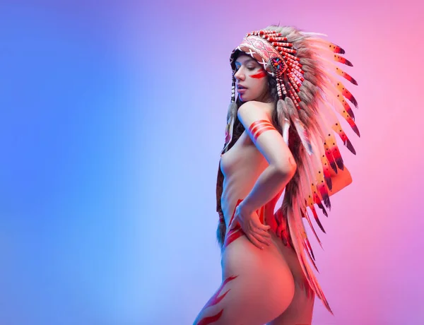 아메리카 원주민 복장을 하고 네온 배경에 깃털을 단 나체의 여성 — 스톡 사진