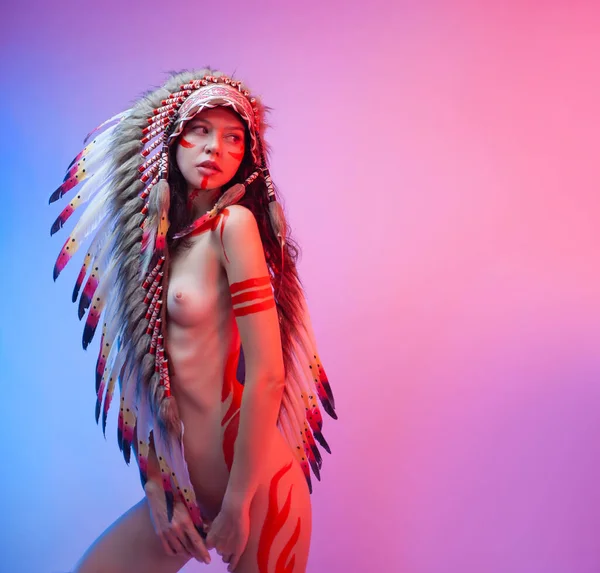 naked woman in native american costume with feathers on a neon background