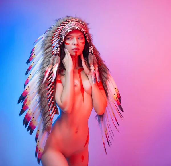 Naked woman in native american costume with feathers on a neon background — Stock Photo, Image