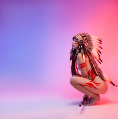 Amerikan yerlisi kostümlü çıplak bir kadın. Arka planda tüyleri var.