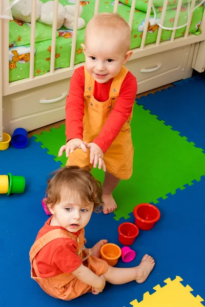 El niño y la niña juegan en un piso de vivero — Foto de Stock