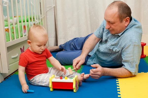 A criança brinca com o pai um brinquedo de madeira com um martelo e o — Fotografia de Stock