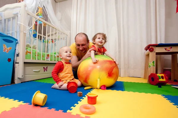 De jongen en het meisje spelen op een kwekerij vloer — Stockfoto