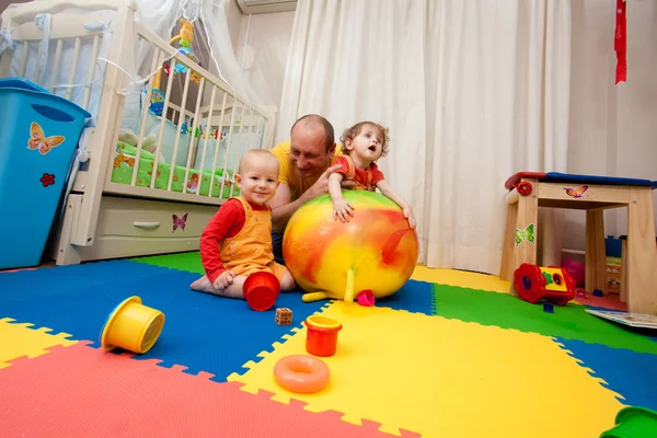 De jongen en het meisje spelen op een kwekerij vloer — Stockfoto