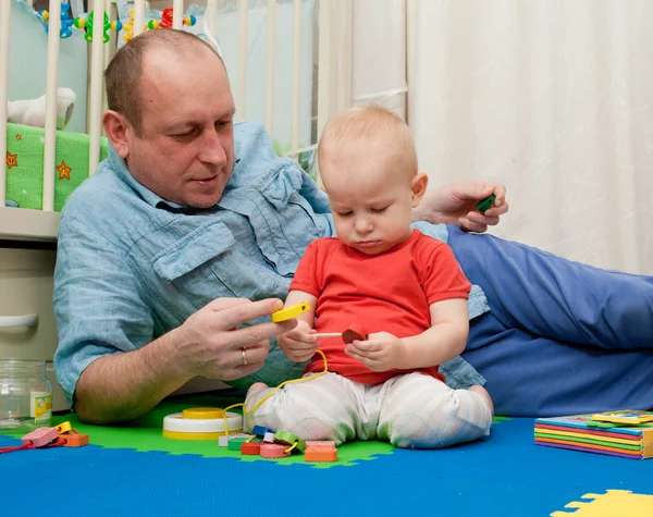 Ungen spelar med fadern en träleksak med en hammare och — Stockfoto