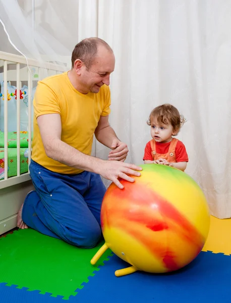 De jongen en het meisje spelen op een kwekerij vloer — Stockfoto