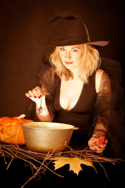 The charming witch cooks the potion on the eve of Halloween. — Stock Photo, Image