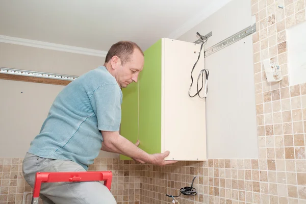 Artesano carpintero de cocina en la instalación del gabinete de cocina serv — Foto de Stock