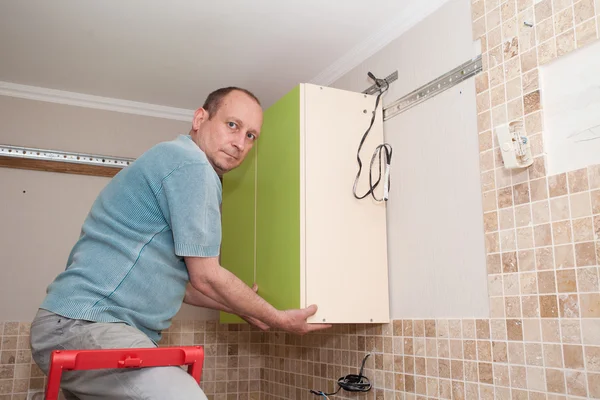 Artesano carpintero de cocina en la instalación del gabinete de cocina serv — Foto de Stock