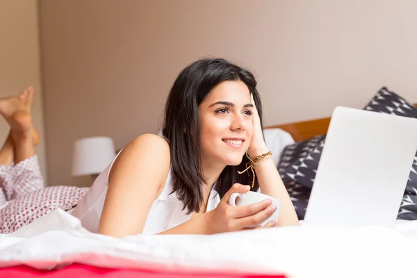 Frau entspannt sich mit ihrem Computer im Bett — Stockfoto