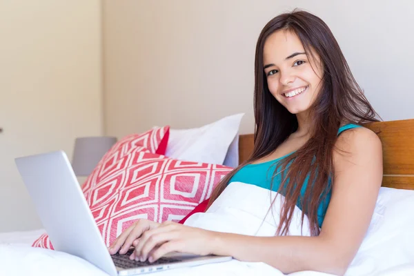 Mujer relajándose con su ordenador en la cama — Foto de Stock