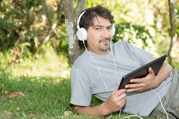 Мужчина расслабляется с планшетом в саду — стоковое фото